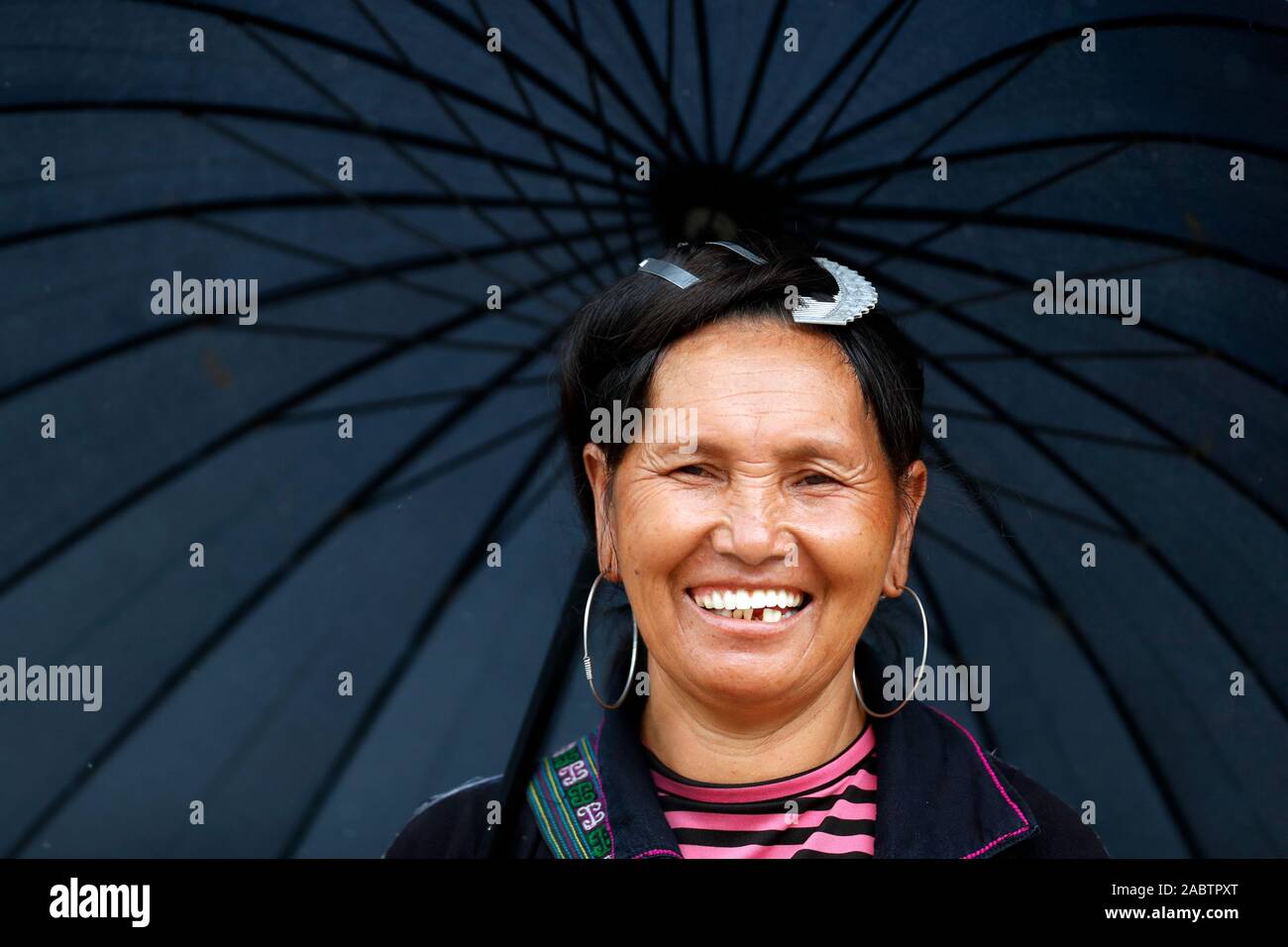 Monsun oder Regenzeit. Lächelnd hmong Frau unter schwarzen Regenschirm. Sapa. Vietnam. Stockfoto