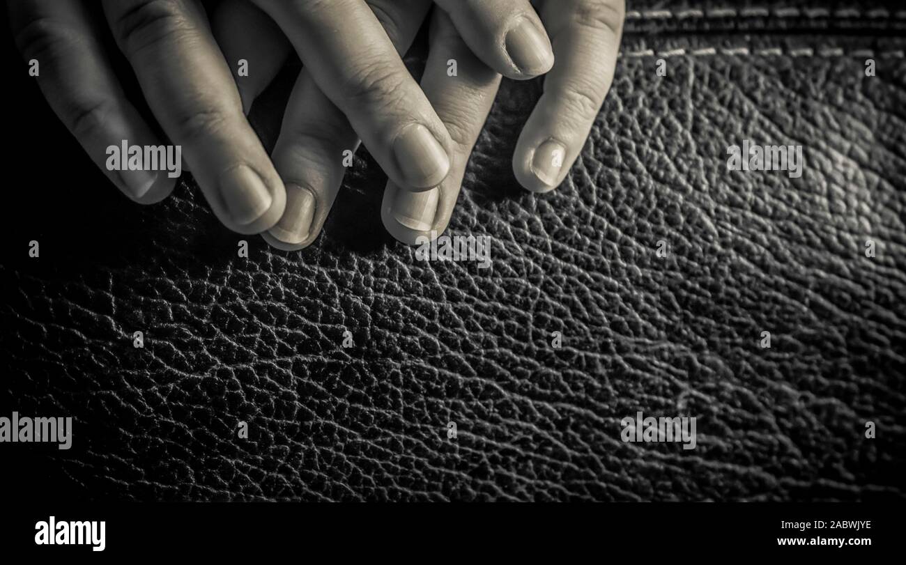 Eine Nahaufnahme der Finger einer Frau auf einem Ledersessel in Schwarz und Weiß Stockfoto