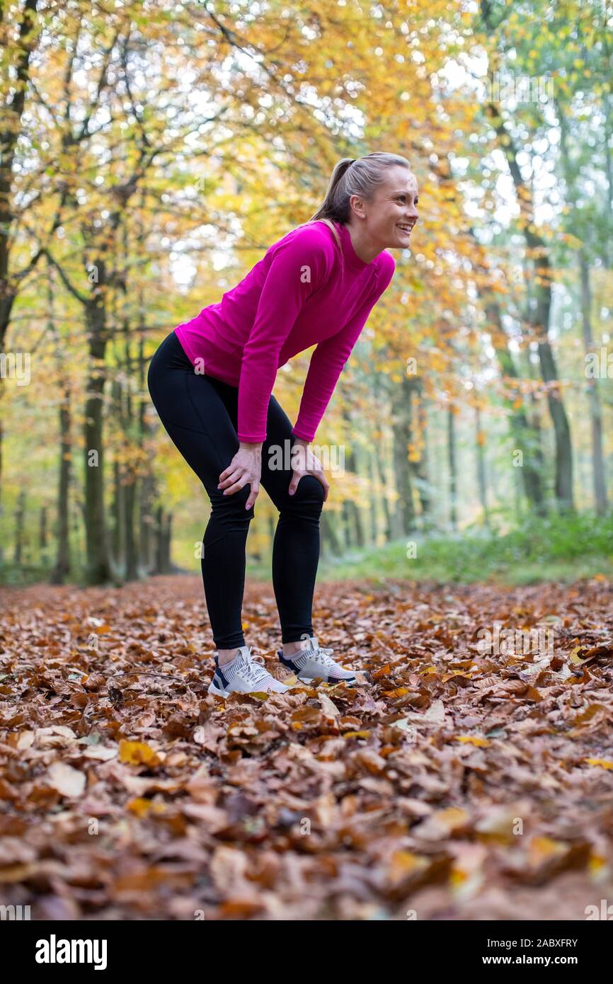 Seitenansicht der Frau am frühen Morgen Herbst Laufen durch den Wald Ausruhen nach Übung Stockfoto