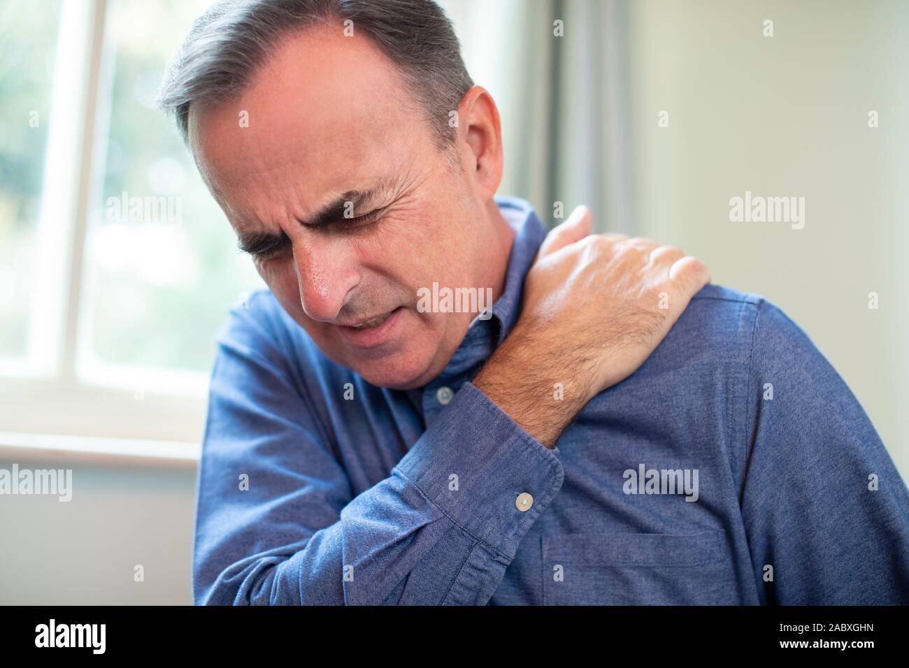 Reifer Mann Leiden mit eingeschlossen Nerv in der Schulter zu Hause Stockfoto