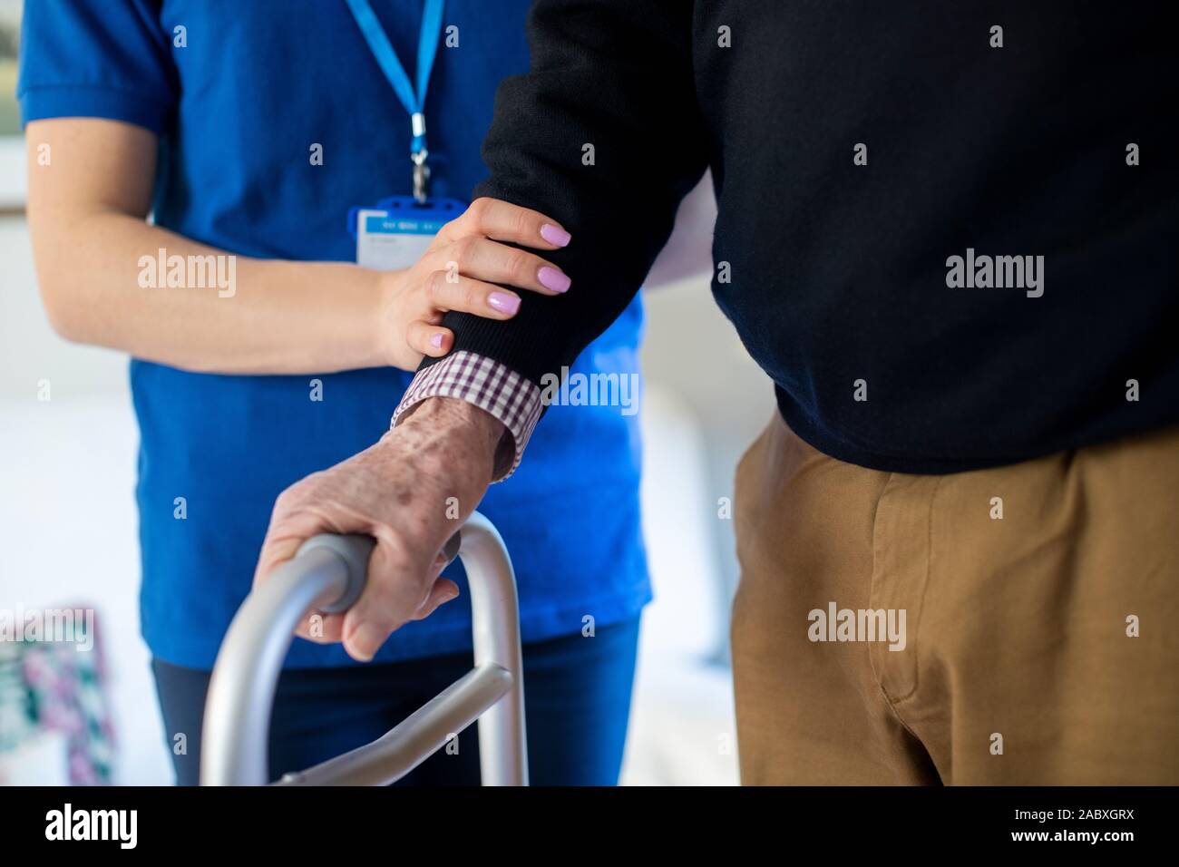 Der ältere Mann mit den Händen auf Gehhilfe durch Care Worker geholfen Stockfoto