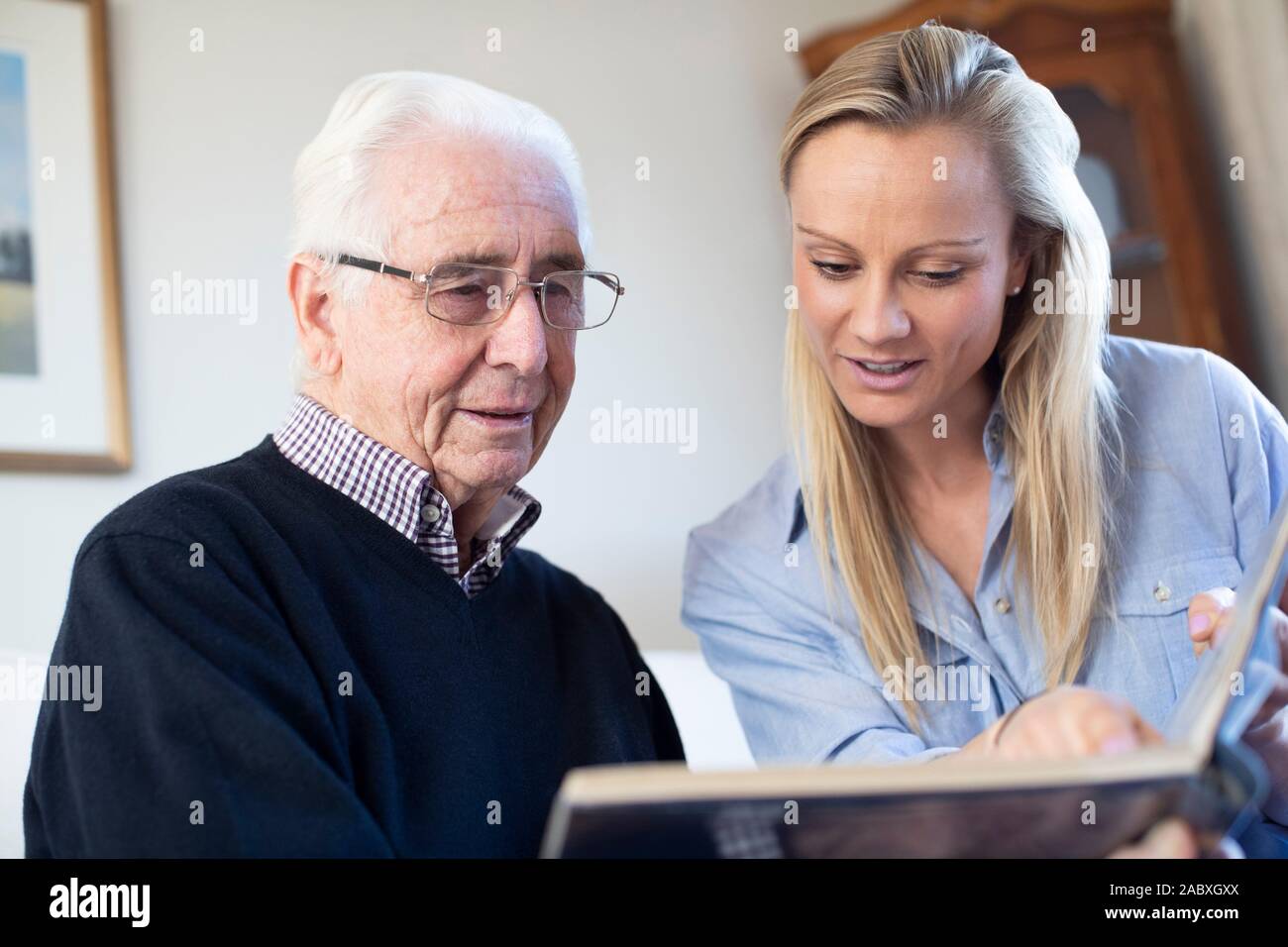 Großvater bei Fotoalbum mit Erwachsenen Enkelin Suchen Stockfoto