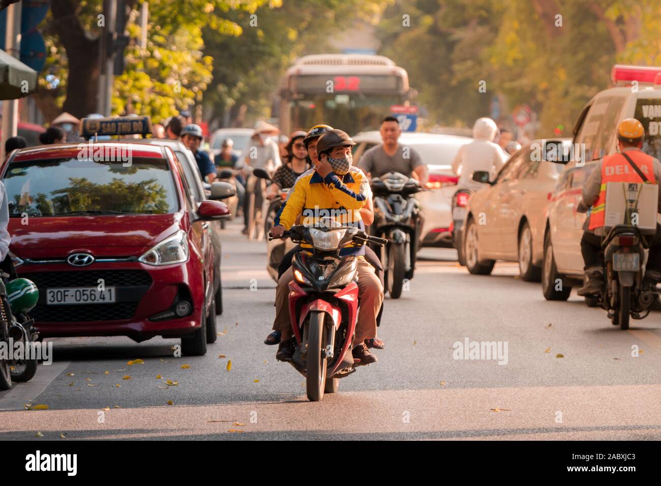 Ein Fahrer und Beifahrer auf einem Moped durch die belebten Straßen von Hanoi Stockfoto