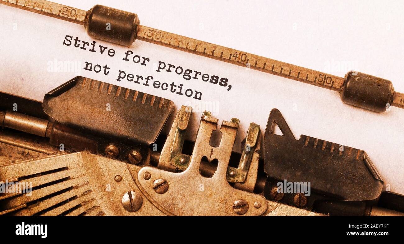 Streben nach Fortschritt, nicht Perfektion - auf einer alten Schreibmaschine geschrieben, vintage Stockfoto