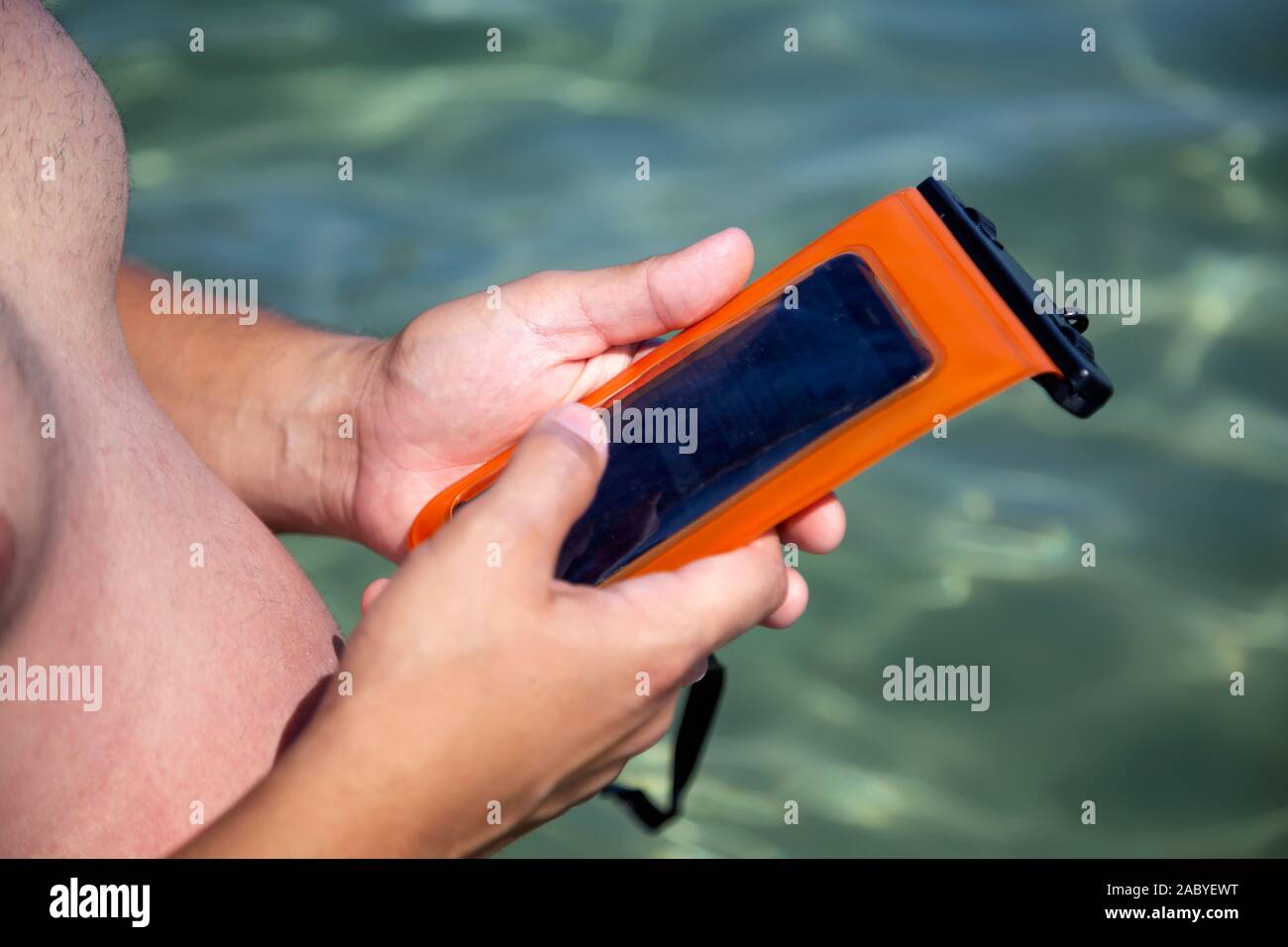 Mann hält eine wasserdichte Tasche für Handy in der Hand, im Meer. PVC-zip Lock bag Handy von Wasser zu schützen. Stockfoto