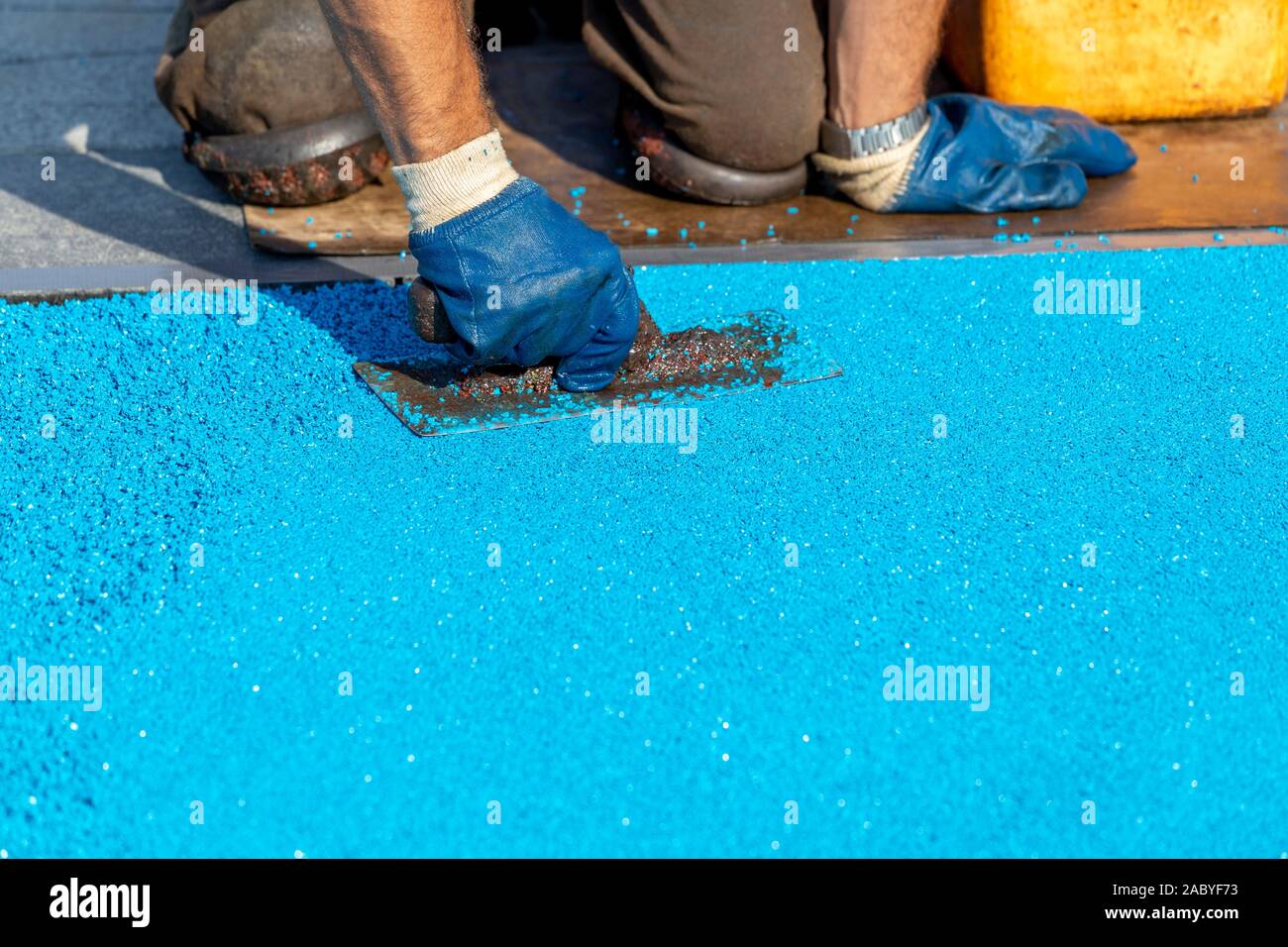 Mason Nivellierung Gummibeschichtung für Spielplätze auf der Oberfläche aufgebracht durch eine stählerne Kelle. PDM Gummigranulat. Selektive konzentrieren. Stockfoto