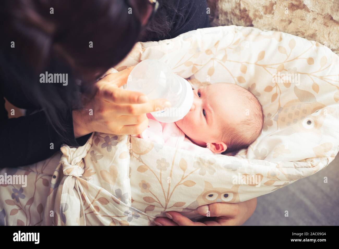 Mutter ist die Fütterung neugeborenes Baby. Eine Frau füttert ein Neugeborenes mit modifizierten Milch aus der Flasche. Ansicht von oben. Stockfoto