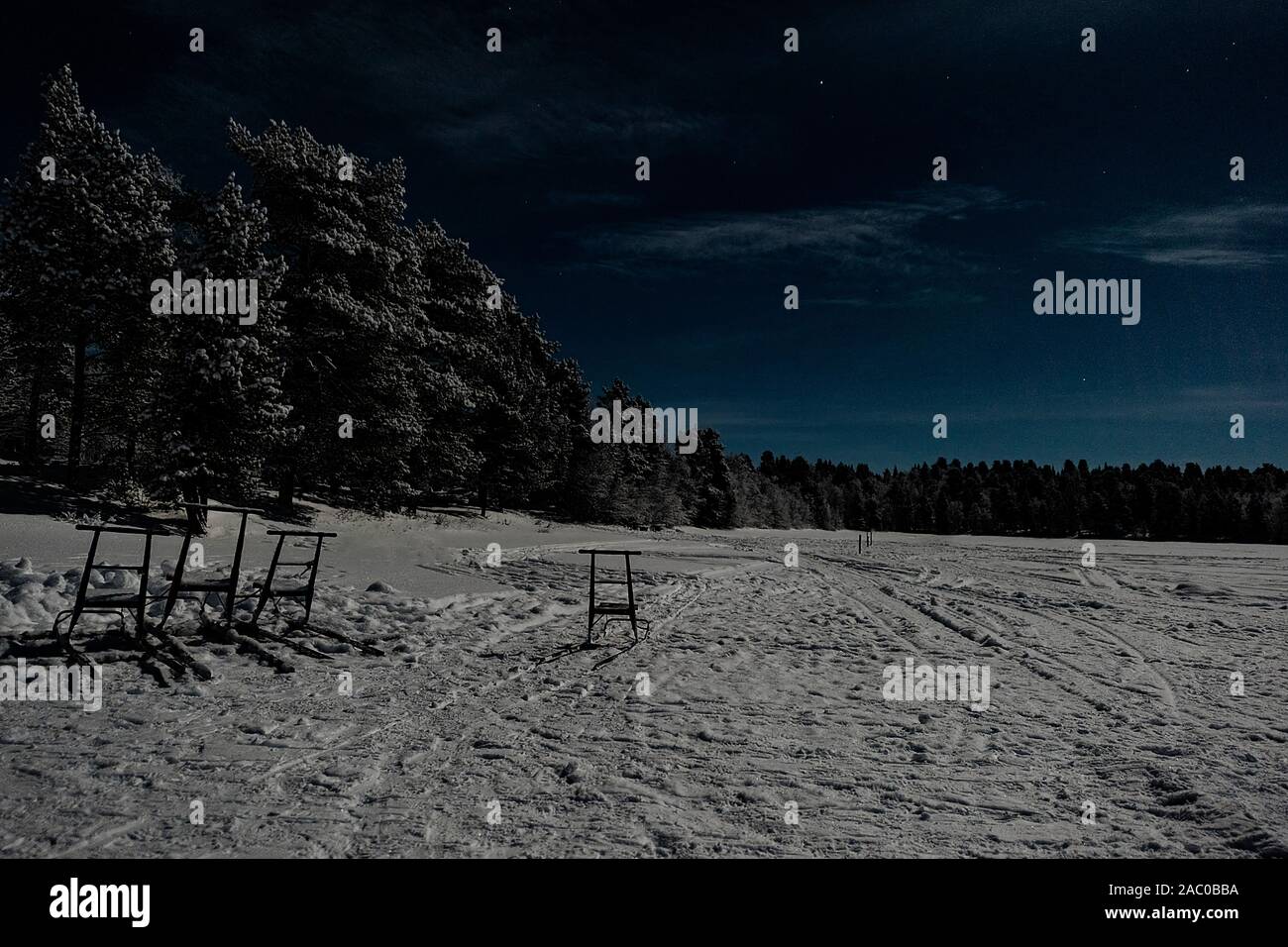 Finnland, Inari - Januar 2019: Lappländische mondbeschienene Winterlandschaft mit Wald und See am blauen Himmel mit vollen Wolke super Mond Stockfoto