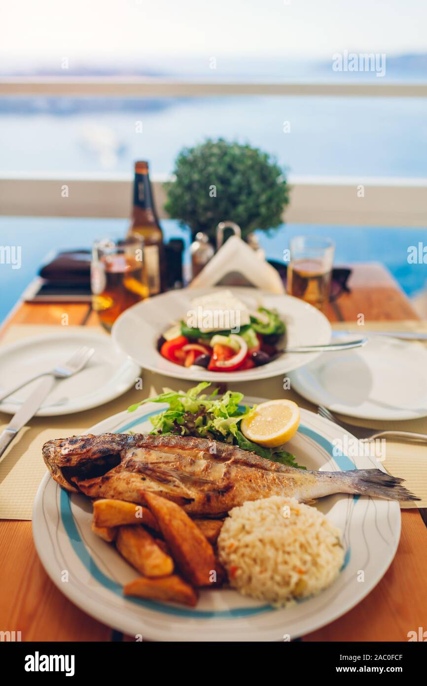 Romantische Hochzeitsreise Abendessen für zwei auf der Insel Santorin, Griechenland mit Meer und Blick auf den Vulkan. Griechischer Salat Fisch und Meeresfrüchte Stockfoto