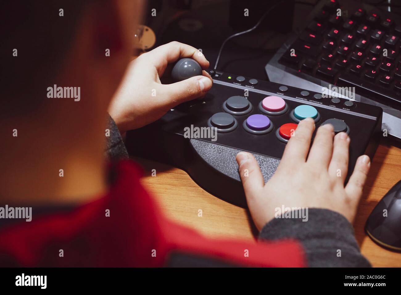 Imperia, Italien, 20.11.2019: Junge, drückt die farbige Schaltfläche eines Arcade pad Vintage video Spiele zu spielen, Fotos von einer normalen Moment des Lebens. Stockfoto