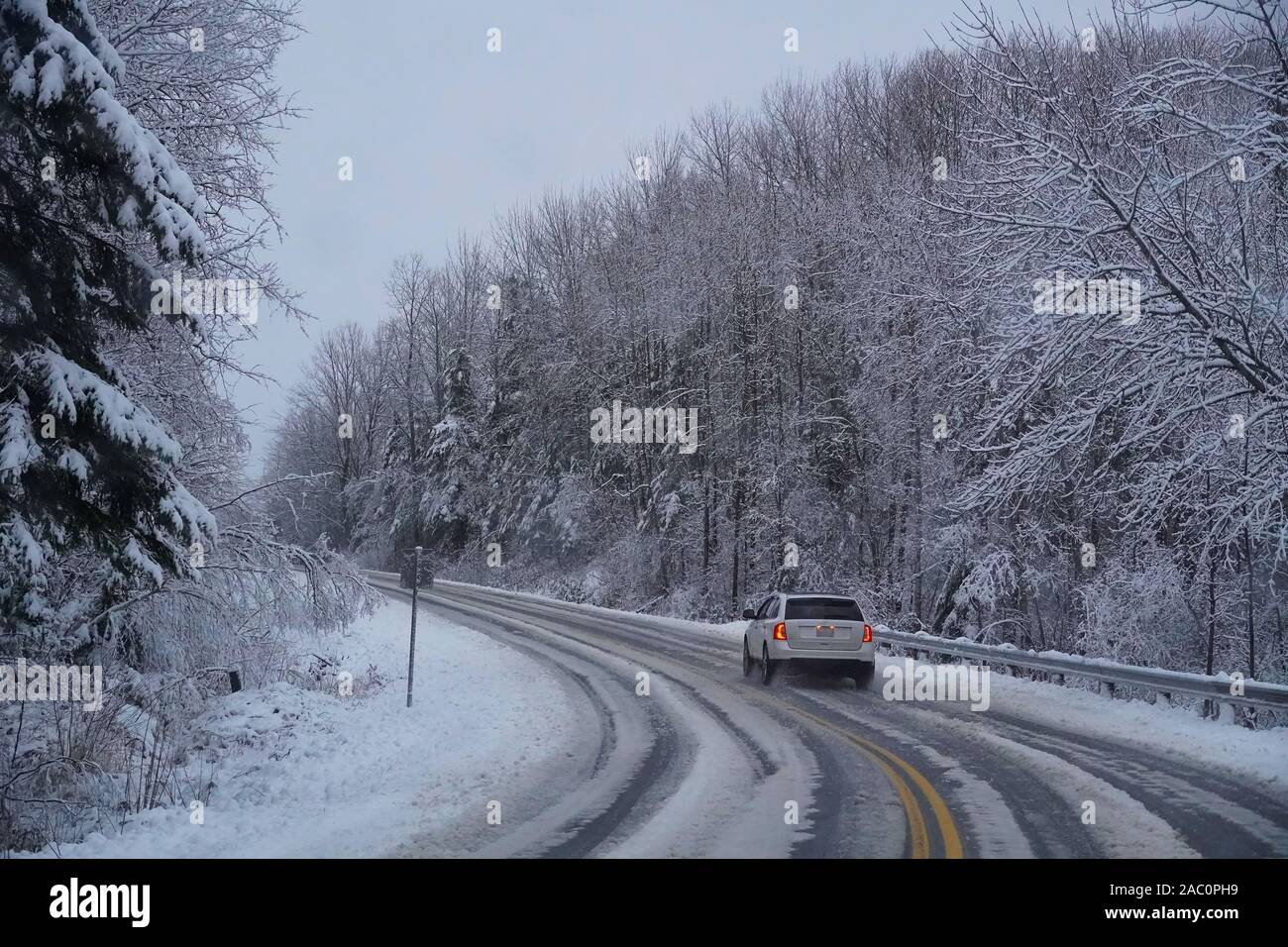 SUV auf gekrümmten Straße in schlechten Straßenverhältnisse und Unfälle im ersten Winter Sturm der Saison. Hübsches weißes Wunderland Stockfoto