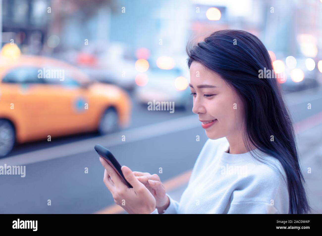 Junge Frau auf der Suche nach Smart Phone in der Stadt bei Nacht Stockfoto