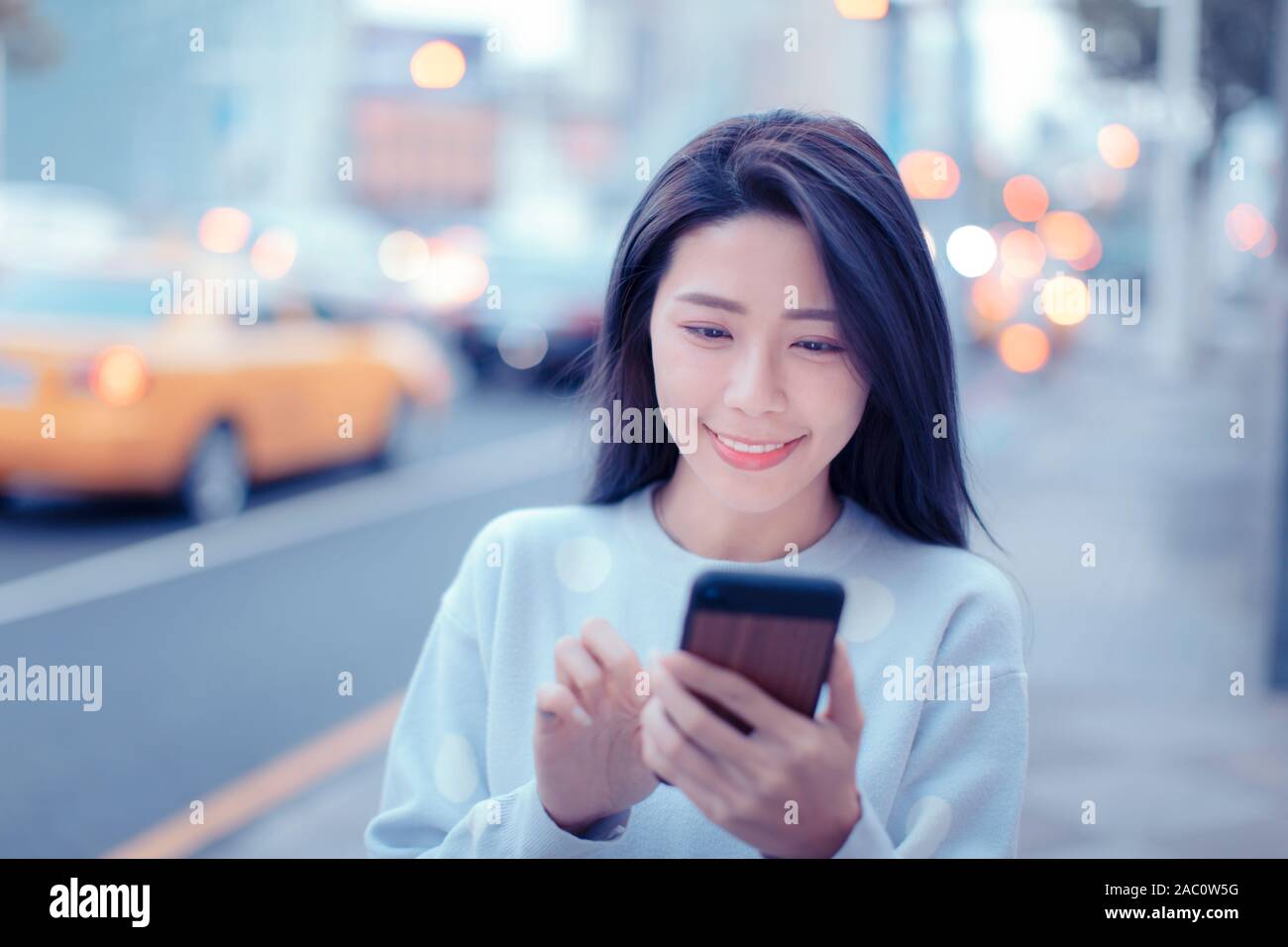 Junge Frau auf der Suche nach Smart Phone in der Stadt bei Nacht Stockfoto
