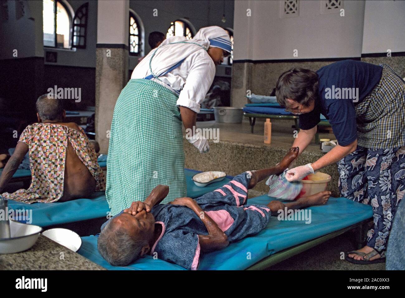 Freiwillige badet Bein eines Patienten bei der Mutter Teresa Haus für Sterbende in Kalkutta, Indien Stockfoto