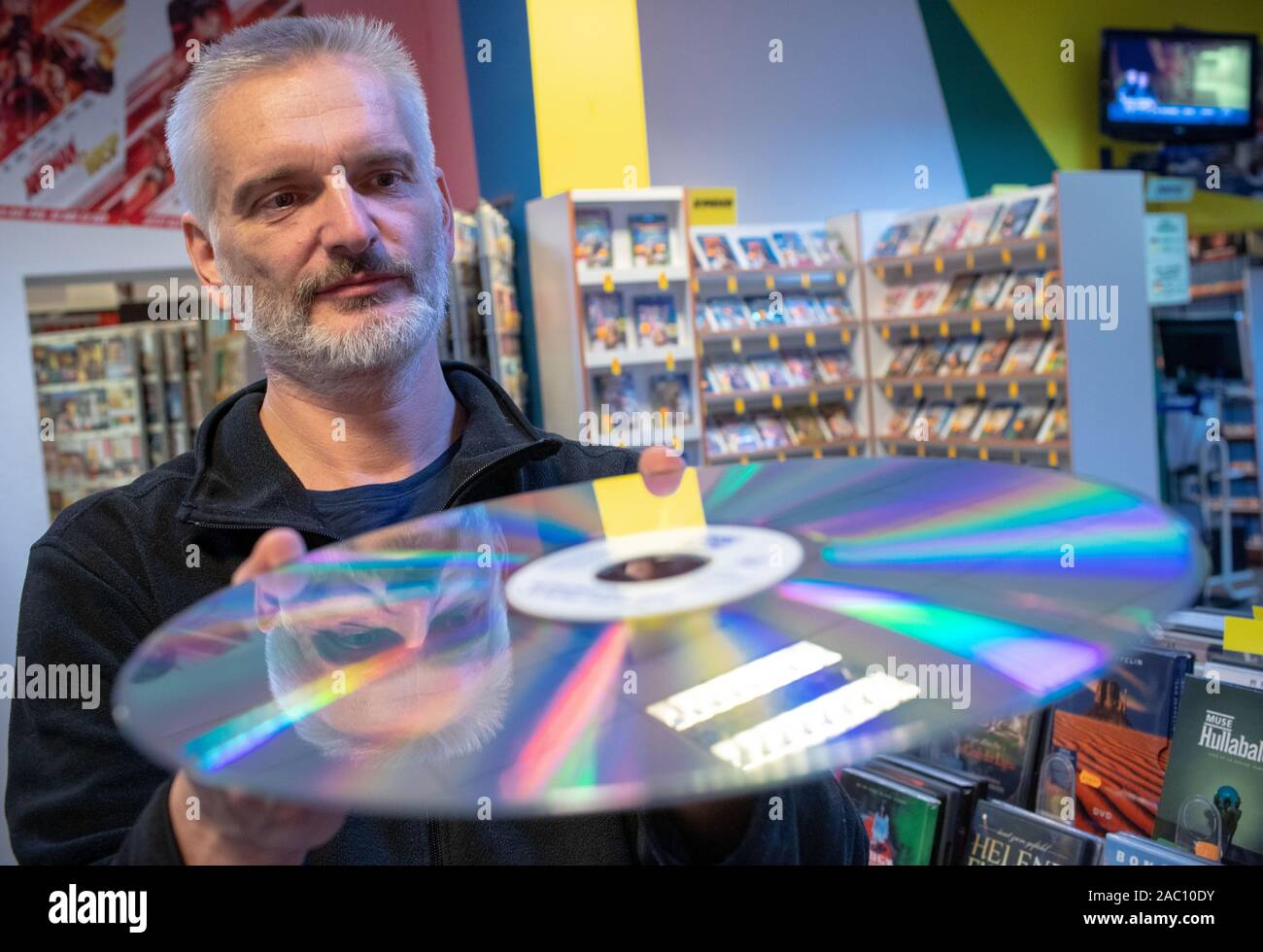 13 November 2019, Mecklenburg-Vorpommern, Parchim: Videothek und Film Experte Maik Micheel zeigt eine seltene Laserdisc (LD), auch Laservisiondisc, in seiner Videothek "Video Aktuell". Das optische Speichermedium mit einem Durchmesser von 30 cm wurde in den 80er Jahren für qualitativ hochwertige Videos. Einer der letzten Video Stores in Mecklenburg-Vorpommern Vorpommern seine Türen schließt nach 29 Jahren vor Weihnachten. 1991 eröffnet, die Vermietung Service für Filme, Musik oder Computerspiele angeboten 3000 VHS-Kassetten und 4.000 DVD oder Blue Ray-Titel auf seiner Hochzeit. Von 9000 Deutschlands Videotheken, es gibt f Stockfoto