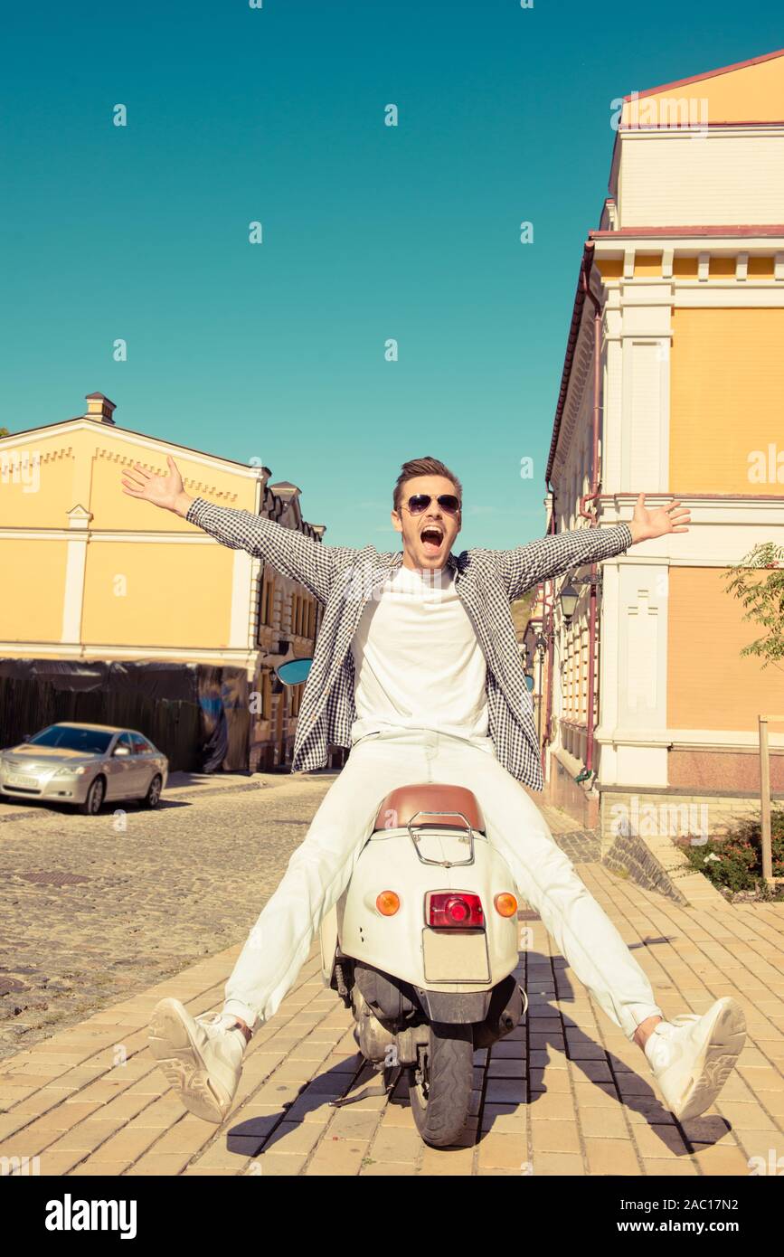 Schöne fröhliche Mann sitzt auf einem Motorroller Stockfoto