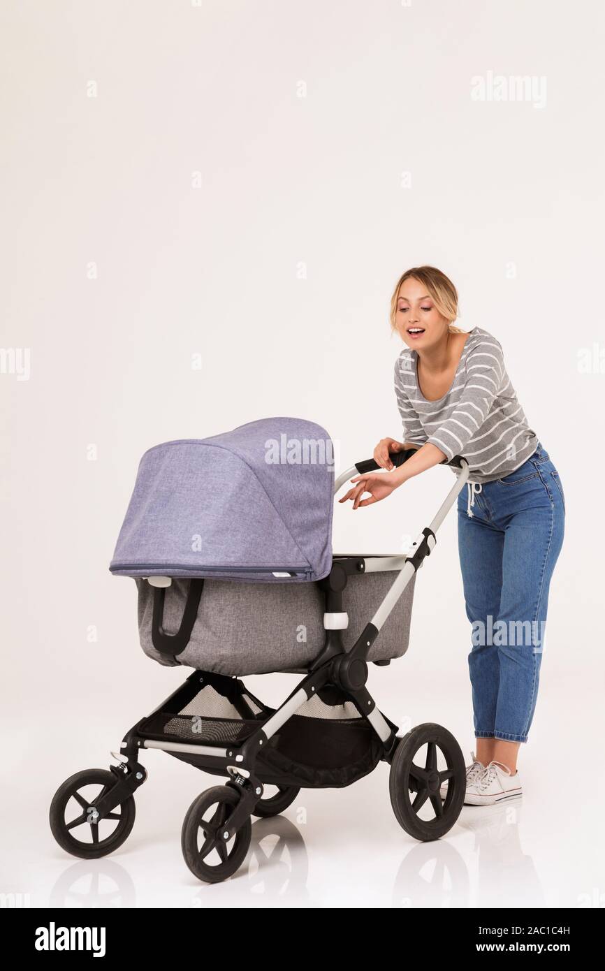Volle Länge des eine schöne junge Frau mit einem Baby Kinderwagen auf weißem Hintergrund Stockfoto