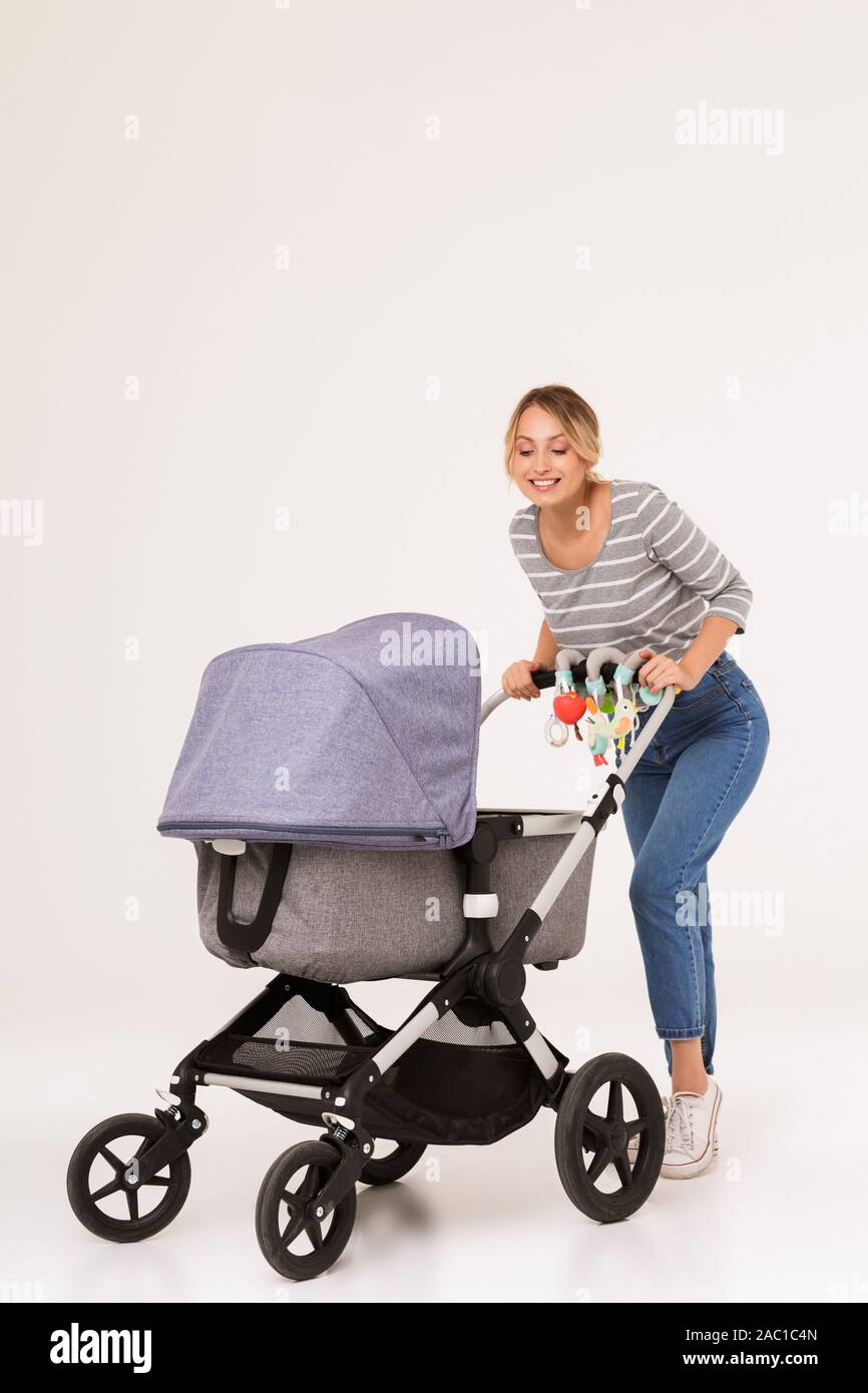 Foto eines wunderschönen positive junge blonde Frau, Mutter mit Baby im  Kinderwagen über weißen Hintergrund Wand isoliert Stockfotografie - Alamy