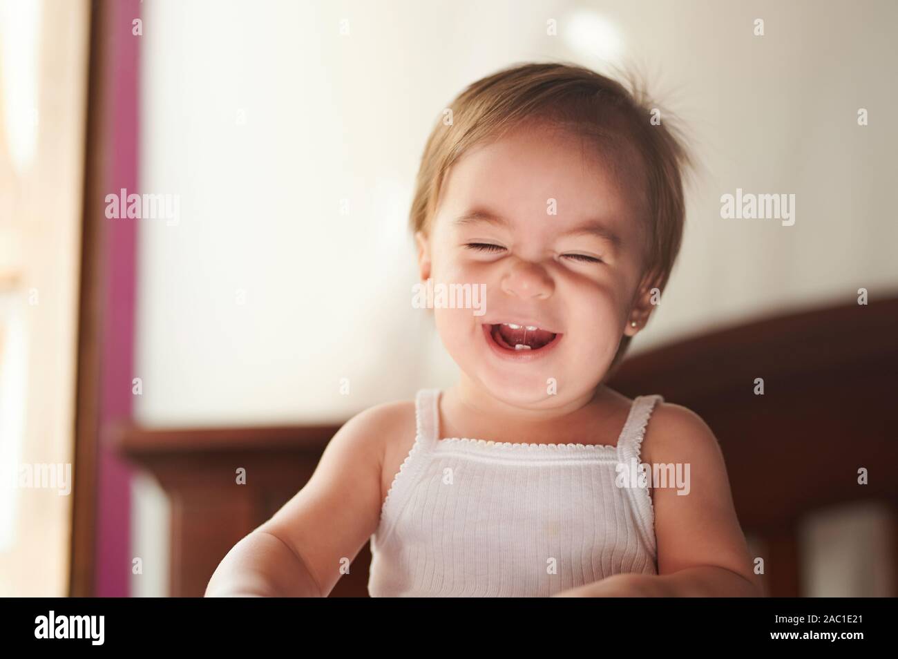 Lachendes Baby mit geschlossenen Augen im weißen T-Shirt Stockfoto