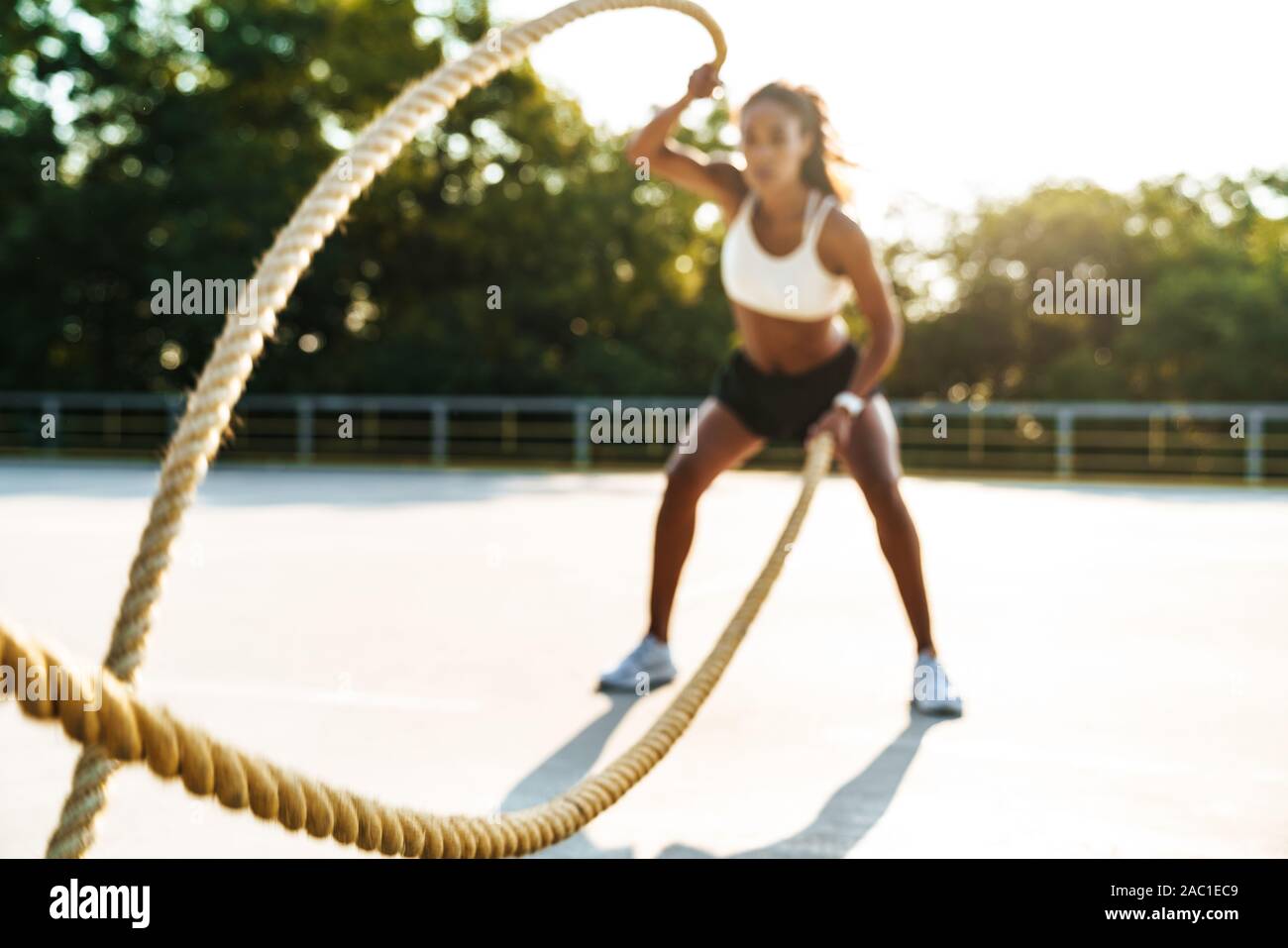 Foto der afrikanischen amerikanischen starke Frau in Sportkleidung tun Workout mit Schlacht Seile an Spielplatz im Freien Stockfoto