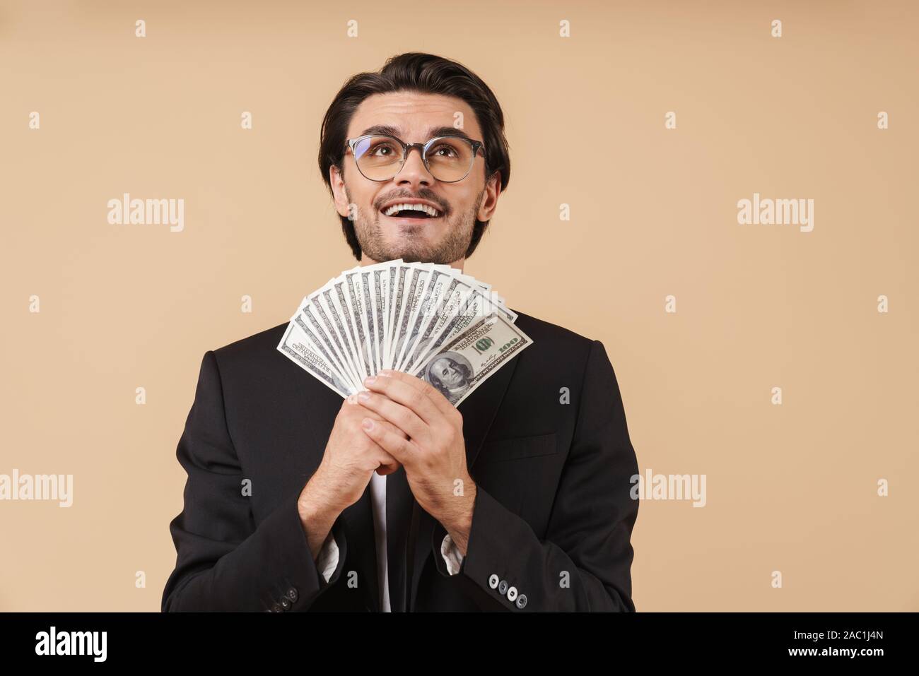 Porträt einer stattlichen junge Unternehmer tragen Anzug stehen über beigen Hintergrund isoliert, mit Geld Banknoten Stockfoto