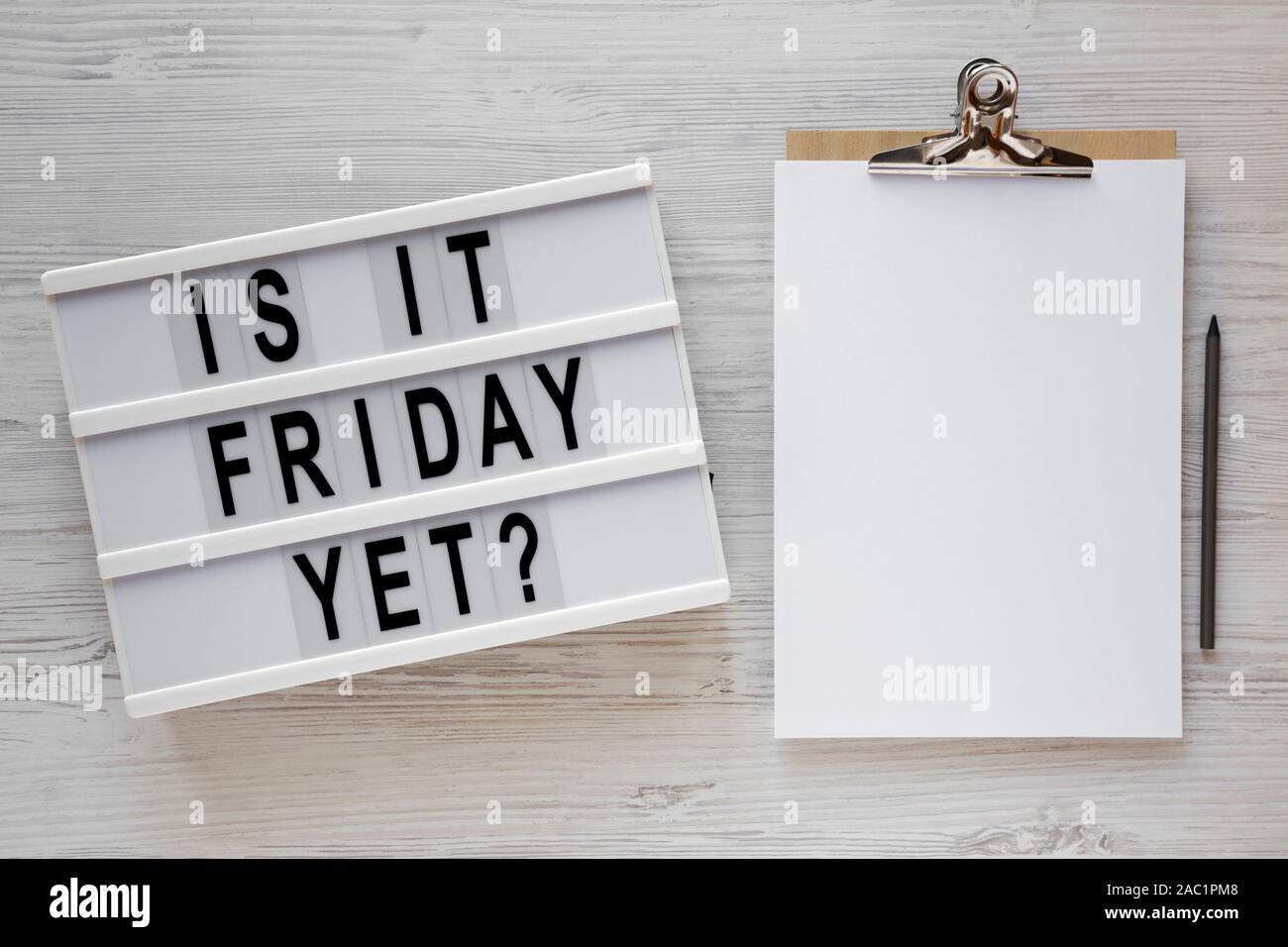 'Ist es Freitag noch?' Worten auf einem modernen Board, Zwischenablage mit leeren Blatt Papier auf einem weißen Holz- Oberfläche, Ansicht von oben. Overhead, von oben, flach. Stockfoto