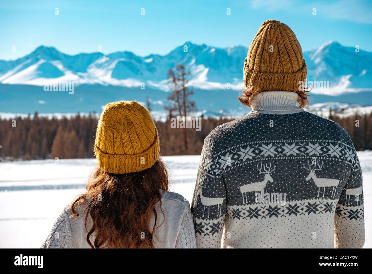 Junges Paar in Pullover und Strick Hüte steht gegen Berge Stockfoto