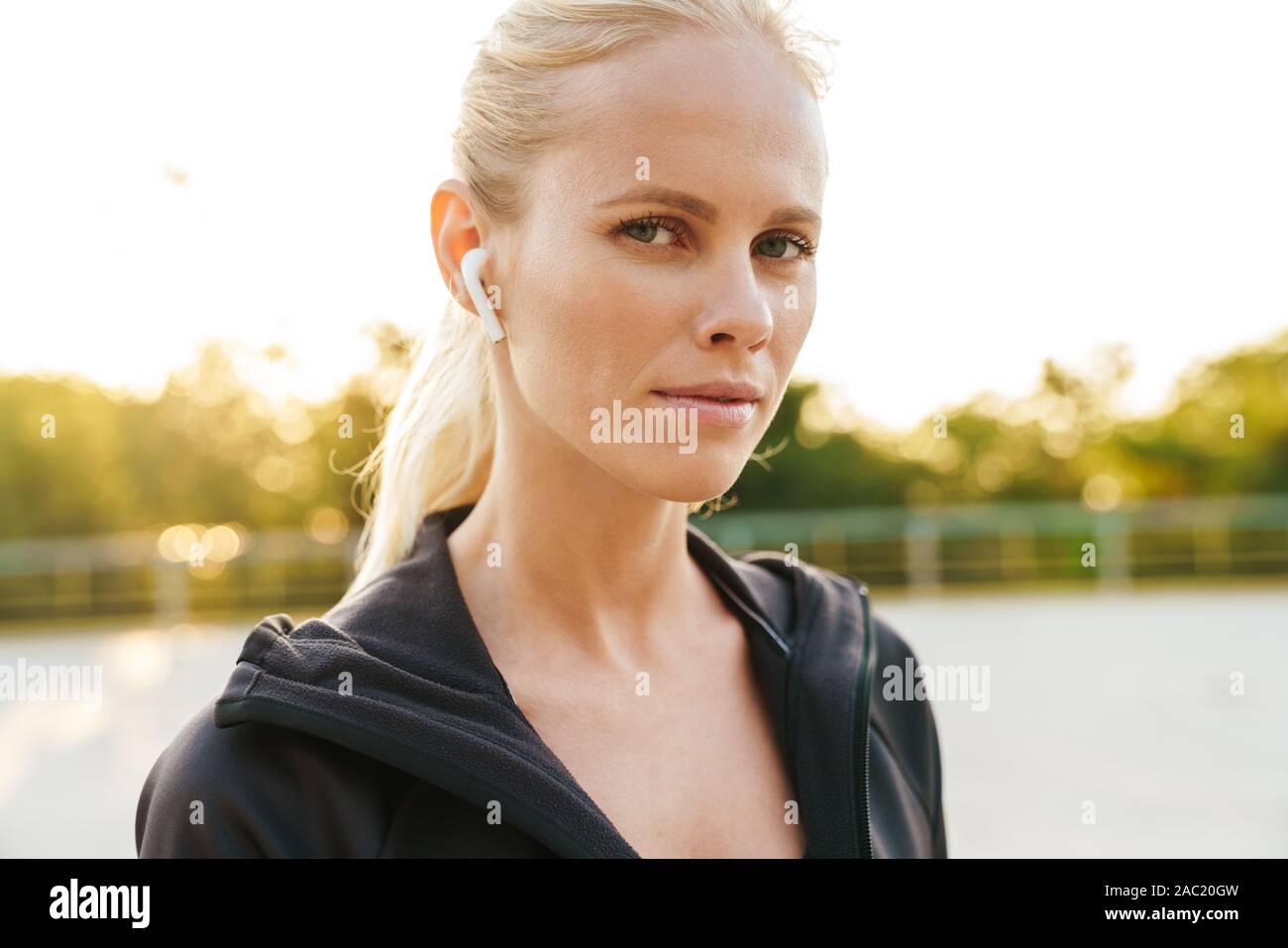 Bild der weiblichen Sportlerin tragen Trainingsanzug und earpods Walking im Freien Stockfoto