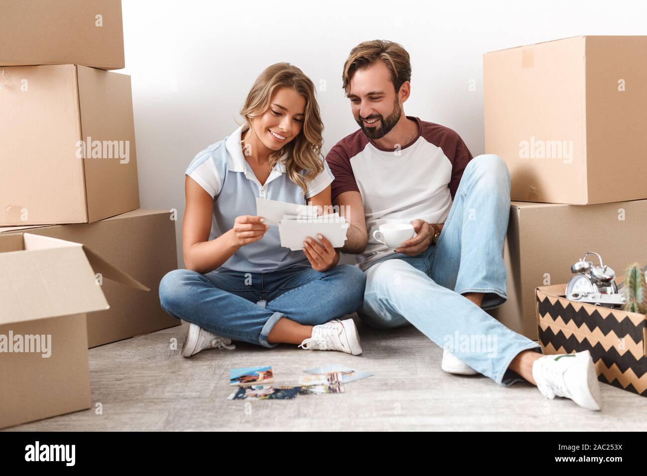 Glückliches Paar schöne Umzug in eine neue Wohnung, sitzen auf einer Etage mit Kästchen umgeben, durch alte Fotos Stockfoto