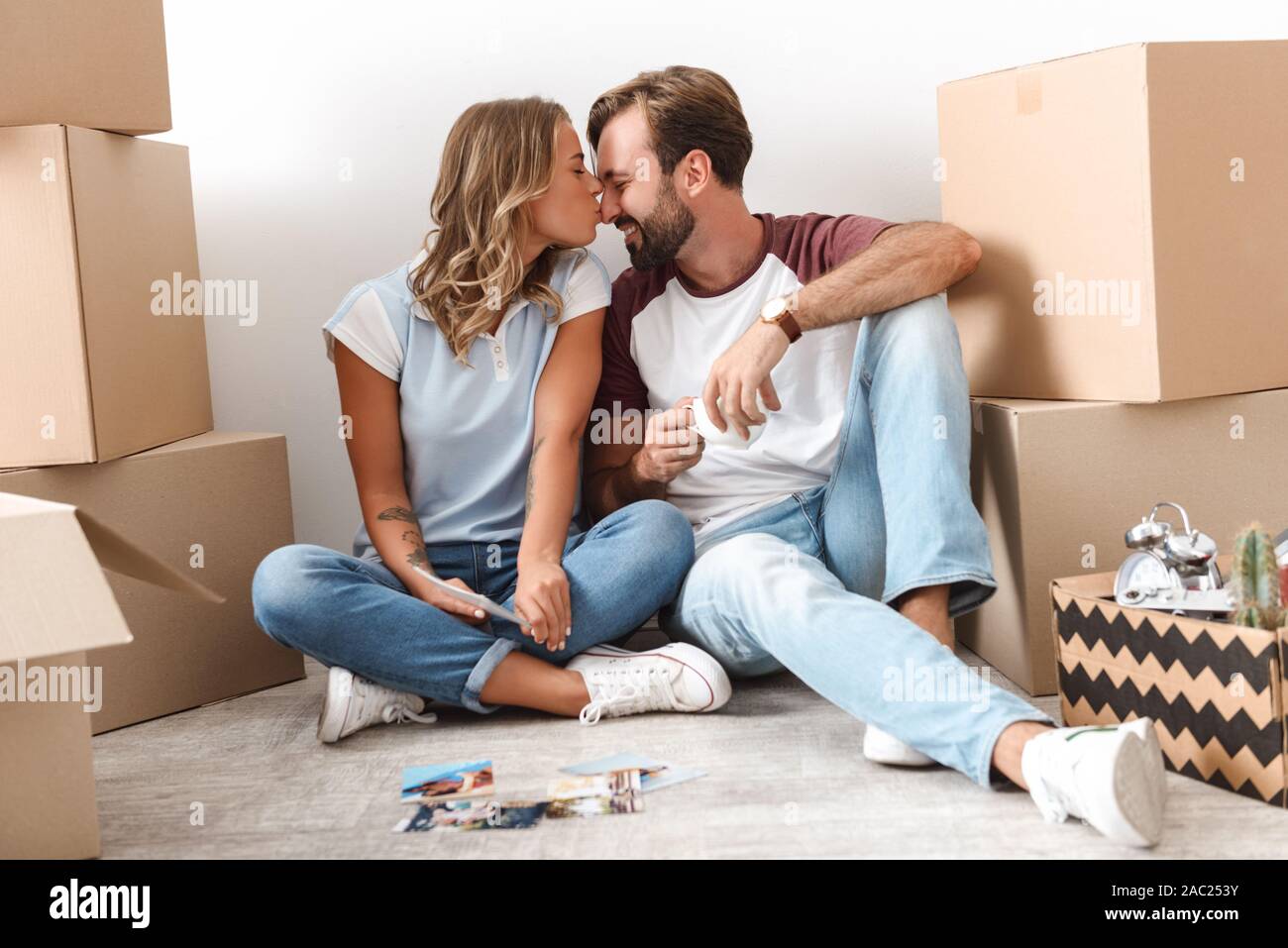 Glückliches Paar schöne Umzug in eine neue Wohnung, sitzen auf einer Etage mit Kästchen umgeben, durch alte Fotos Stockfoto