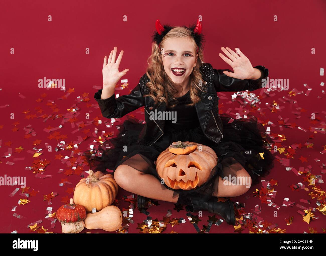 Bild von fröhlichen gerne kleine Mädchen Teufel Karneval halloween kostüm  über rote Wand Hintergrund holding Kürbis isoliert Stockfotografie - Alamy