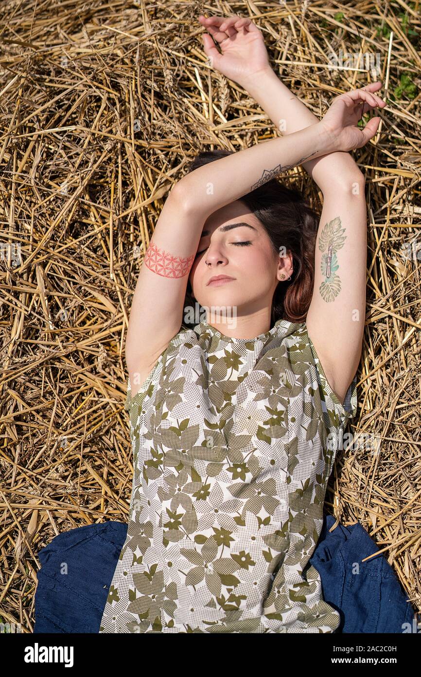 Mädchen liegt und Träumen in einem Weizenfeld. Frau posiert auf Heu trockenes Gras, Sommersaison. Entspannung in der Natur. Einstellung zurücksetzen Stockfoto