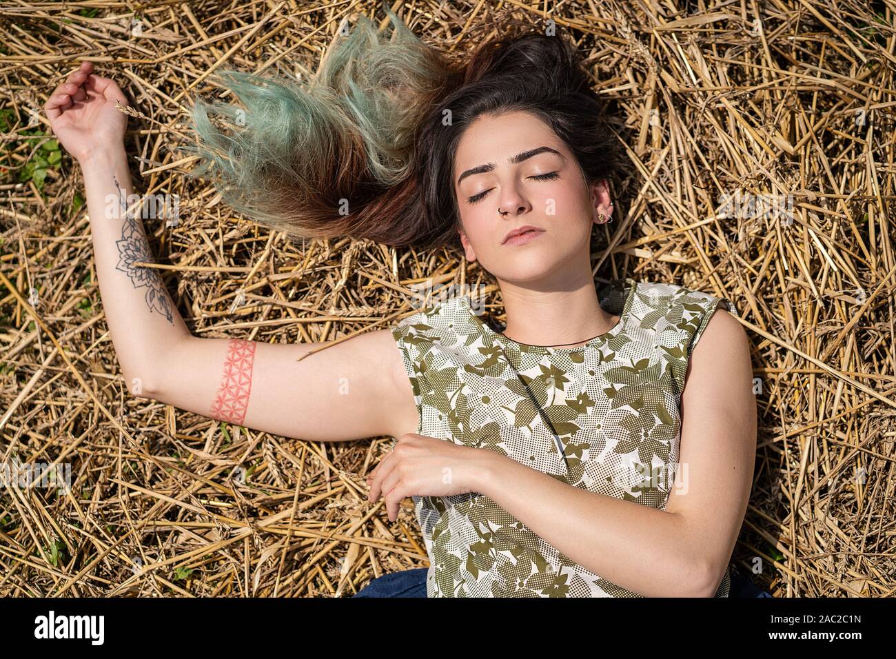 Mädchen liegt und Träumen in einem Weizenfeld. Frau posiert auf Heu trockenes Gras, Sommersaison. Entspannung in der Natur. Einstellung zurücksetzen Stockfoto