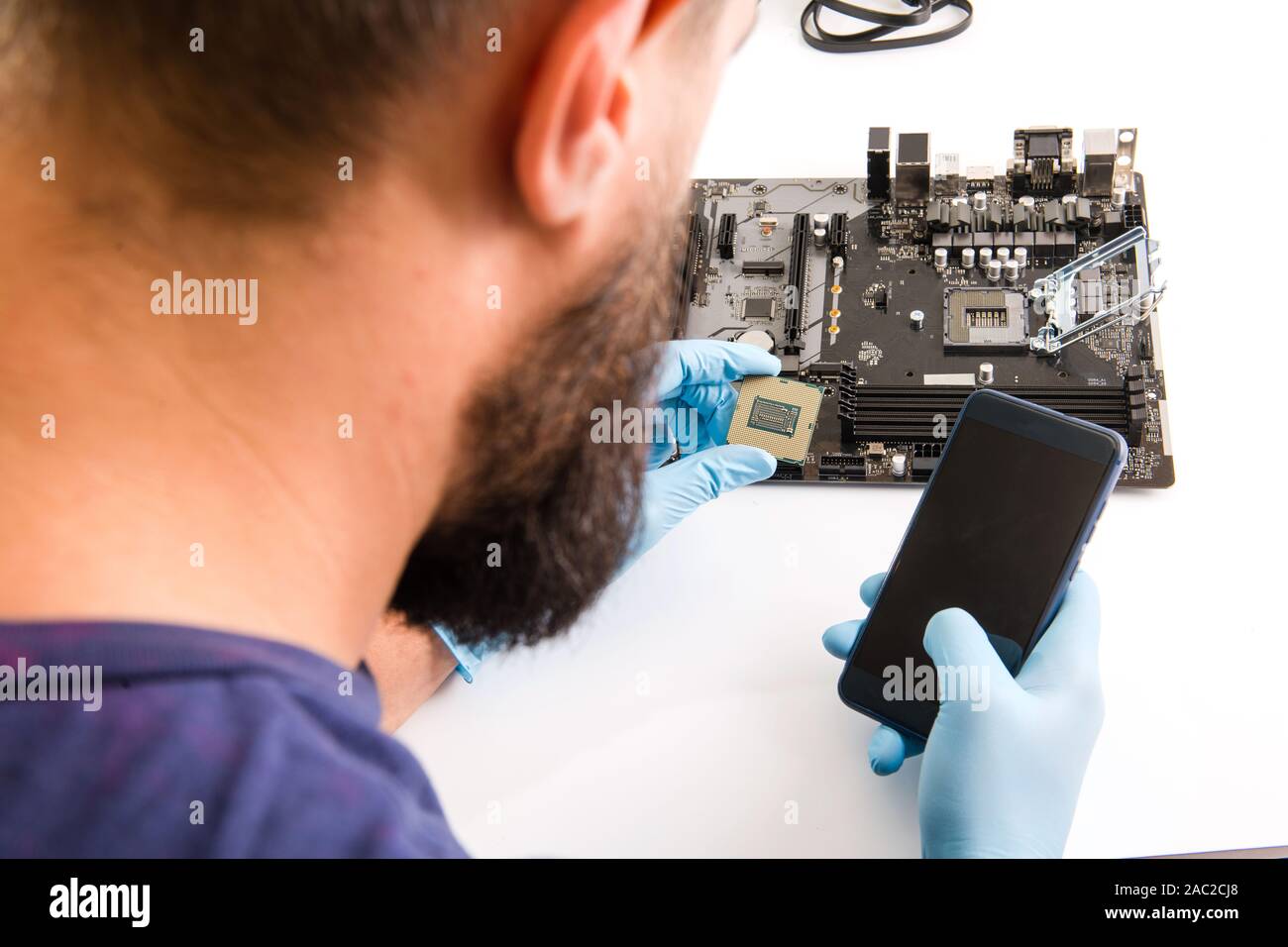 Computer Master prüfen Telefon während Installation der CPU Stockfoto