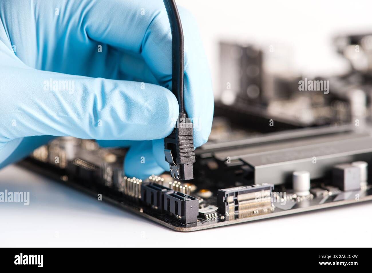 Anschluss von SATA-Kabels mit der Hauptplatine des Computers. Close-up. Weißer Hintergrund. Stockfoto