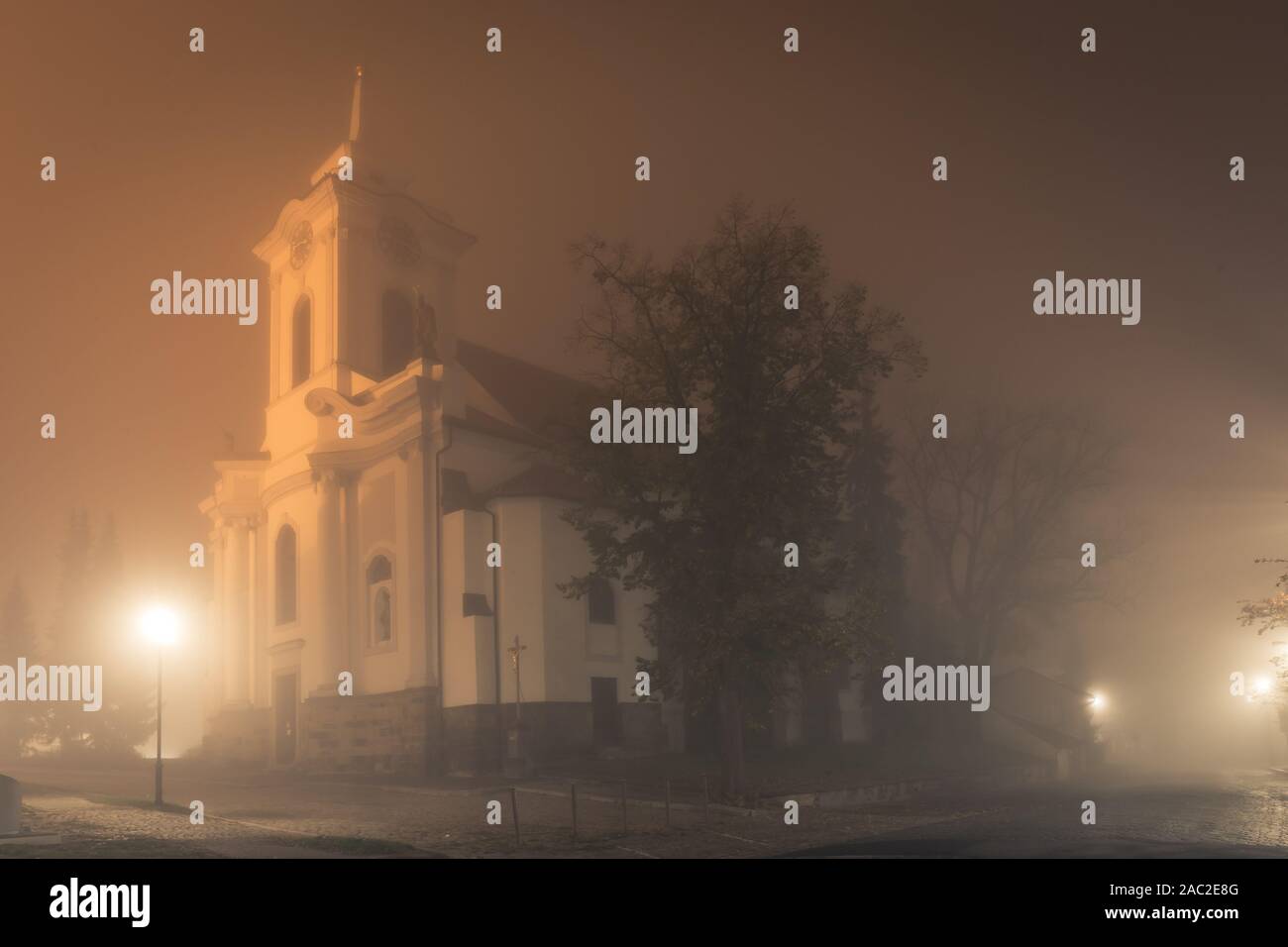 Alte Kirche in Nebel in der Nacht, St. Gotgard Kirche in Cesky Brod, Südböhmen Region Tschechische Republik. Spooky Herbst oder Winter Szene. Stockfoto