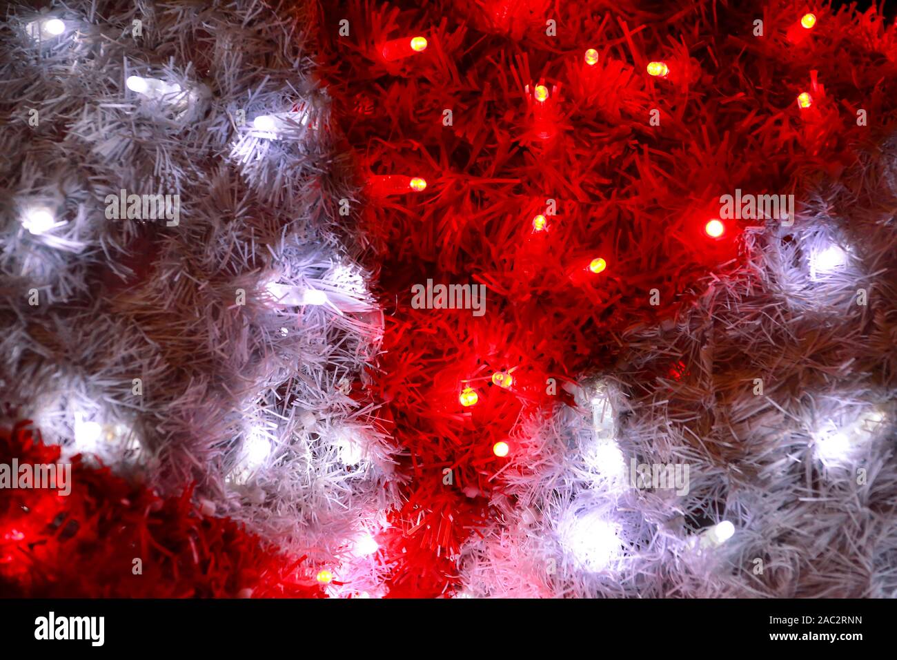 Teil von Weihnachten dekorative rote und weiße Blinkleuchten, hautnah. Straße Detail des Neuen Jahres und Weihnachtsschmuck, string Reis Glühlampen. Stockfoto
