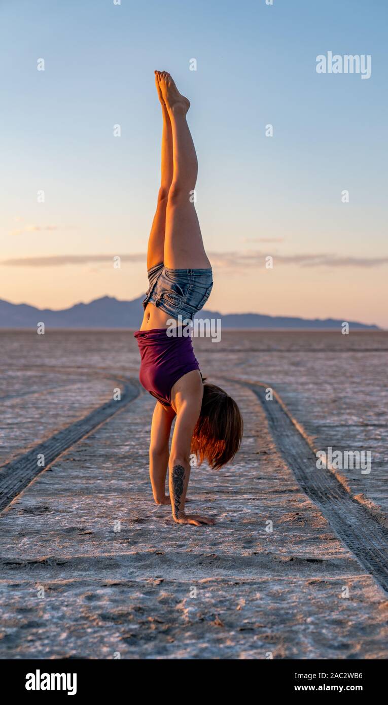 Schöne Frau macht Handstand während des Sonnenuntergangs in der Bonneville Salt Flats Stockfoto