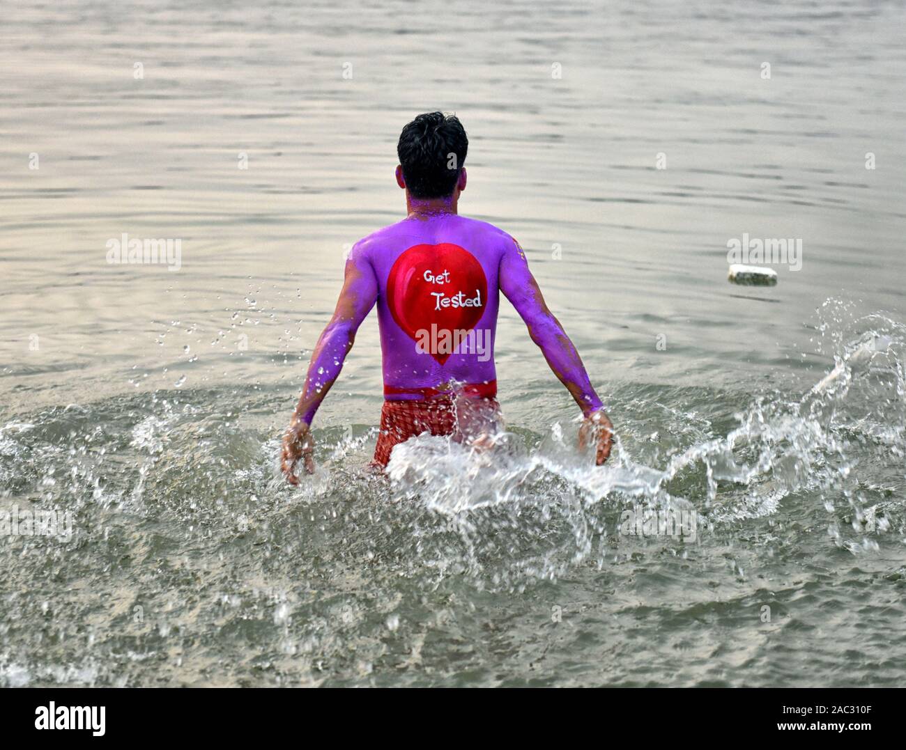 Ein Mann mit einem Malerei an seinem Rücken sagen 'getestet' bewegen im Wasser während des Welt-AIDS-Tag Welt-AIDS-Tag am 1. Dezember jedes Jahr seit 1988. Es ist eine Internationale Tag zur Sensibilisierung der AIDS-Pandemie durch die Ausbreitung der HIV-Infektion verursacht und Trauer, die an der Krankheit gestorben sind. Stockfoto