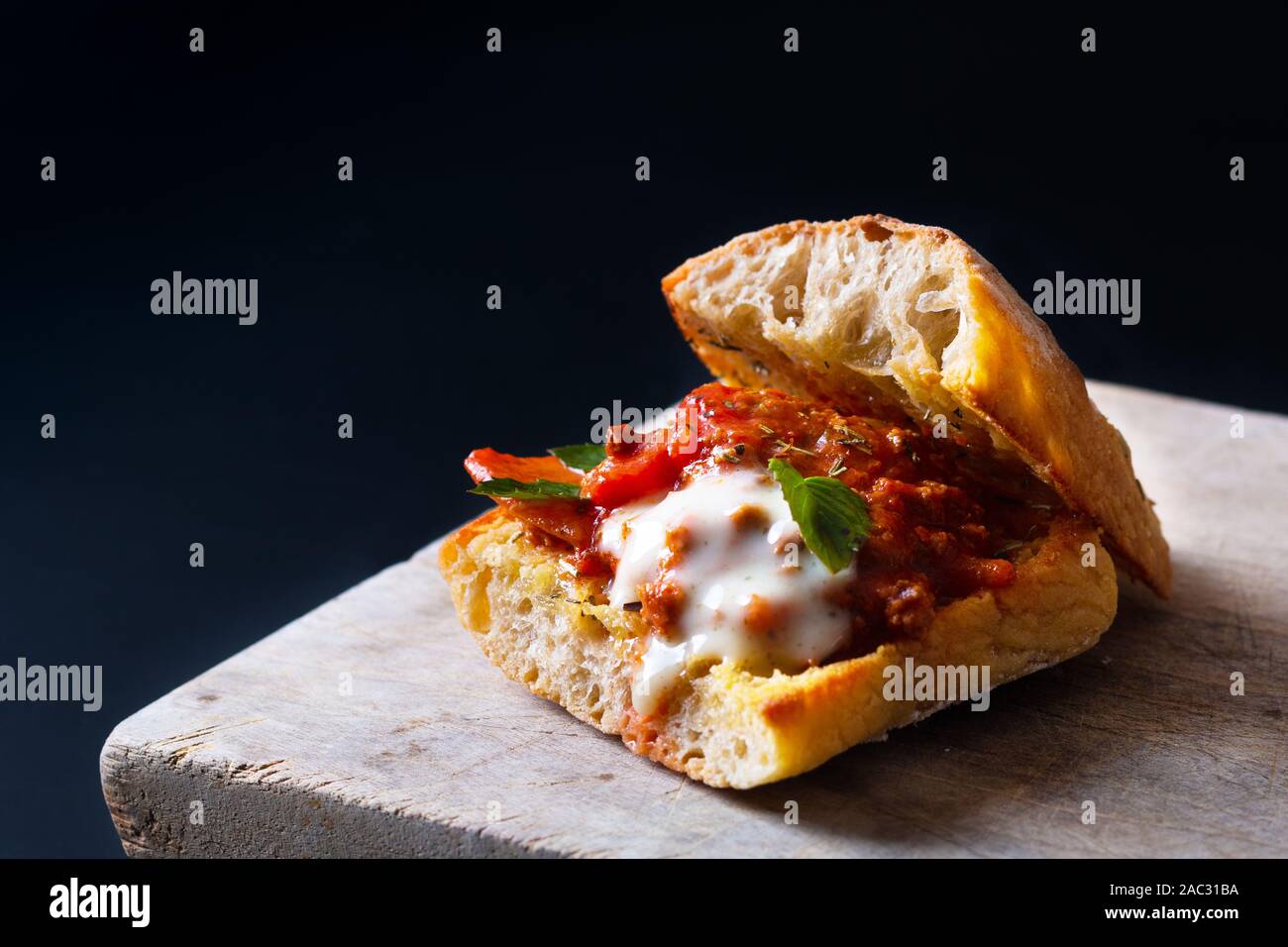 Hausgemachte Speisen Konzept Organische bolognese Grill Artisan Brot Sandwich auf schwarzen Hintergrund mit Kopie Raum Stockfoto