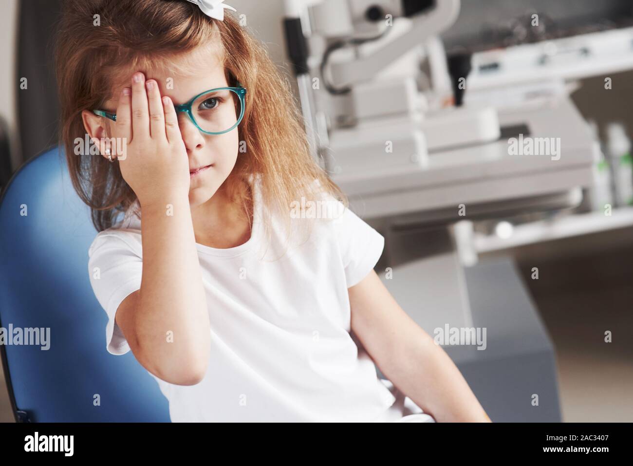Das rechte Auge mit der Hand. Kleines Mädchen seine Vision mit neuer Brille prüfen Stockfoto