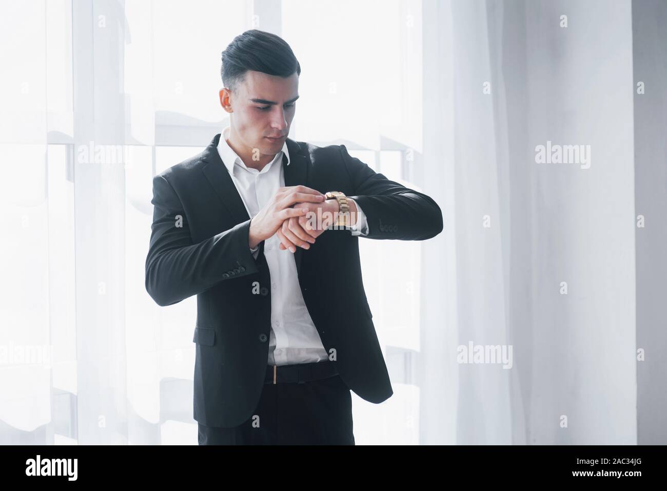 Der Mensch in der klassischen Anzug Kontrollen Zeit auf seinen Luxus goldene Uhren Stockfoto