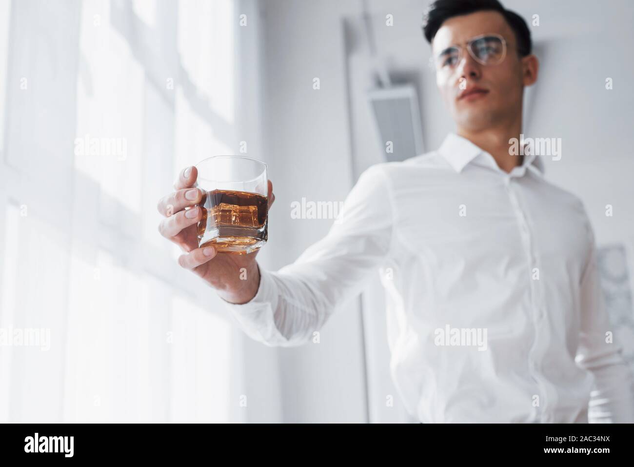 Nähe zu sehen. Wunderschöne Mann in Brillen stehen Innen- und Halten der Alkohol Stockfoto