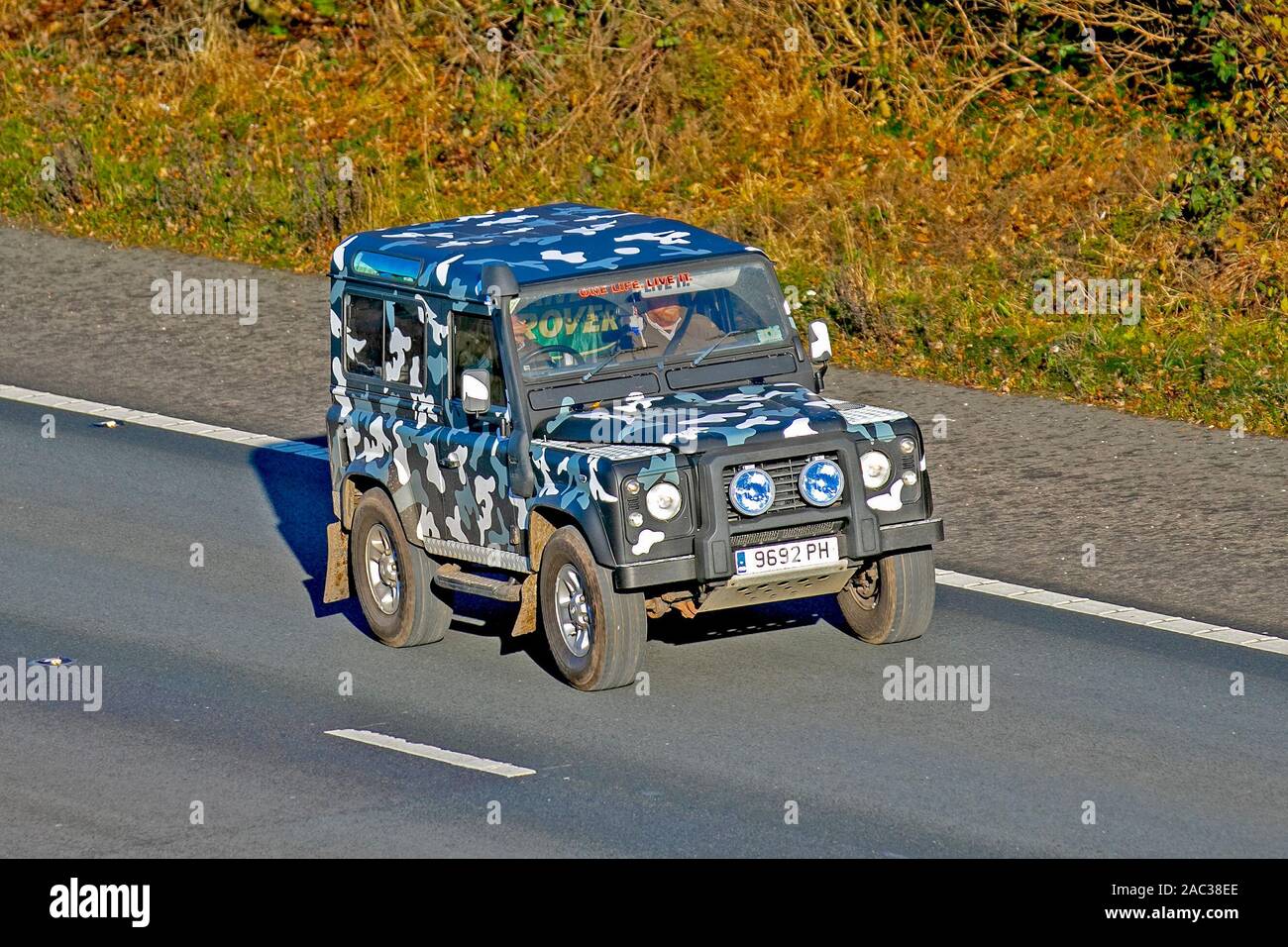 2006 Mehrfarbige Custom Land Rover Defender 90 Schwarz H/T; mit Schnorchelauslass, UK Fahrzeug Verkehr, Camouflage Transport, moderne Fahrzeuge, Limousinen, getarnte Fahrzeuge, Fahrzeug, uk Straßen, Motoren, auf der dreispurigen Autobahn M61 nach Süden fahren Stockfoto