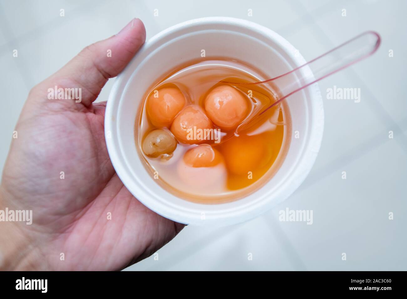 Hand hält eine Schüssel mit Klößen. (Tangyuan oder Tang yuan (Chinesische Schatz Suppe) ist ein chinesisches Dessert aus klebreis) Stockfoto