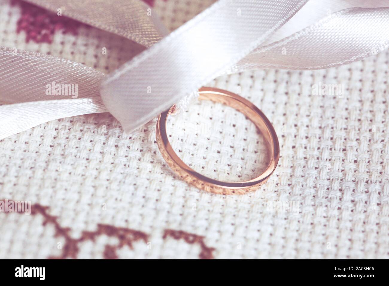 Details einer Hochzeit Ring mit weißem Band und legte auf einem bestickten Stoff Stockfoto