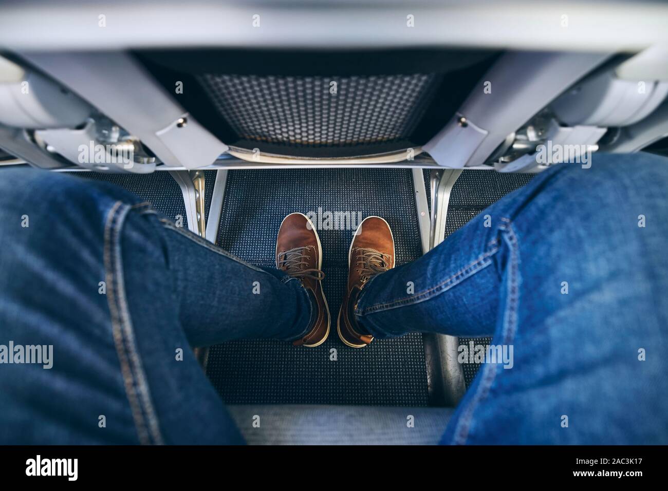 Beinfreiheit zwischen den Sitzen im Flugzeug. Persönliche Perspektive des Personenverkehrs auf der Strecke in der Economy Class. Stockfoto