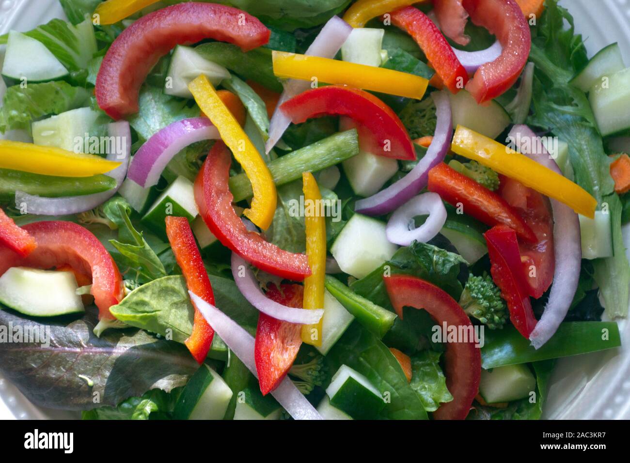 Nahaufnahme eines delectably frischer Salat zum Bersten mit Ernährung und coloful Gemüse einschließlich Feder Mix Grüns, Spinat, Gurken, Tomaten, roten Oni Stockfoto