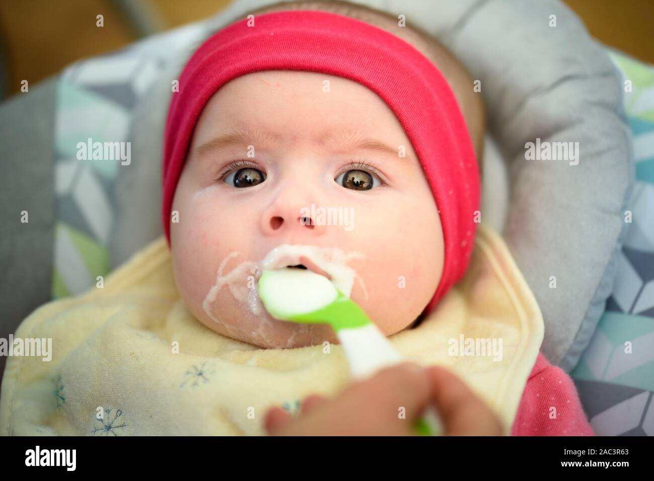 Mutter Fütterung hungrigen fünf Monate altes Baby mit Löffel, feste Nahrung. Neugeborene Fütterung Konzept Stockfoto