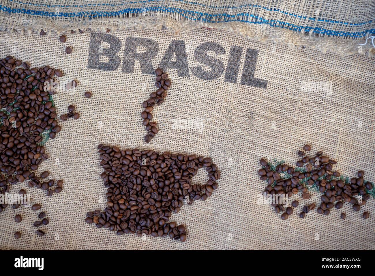 Kaffeebohnen auf Jute Sack und gedruckten Brasil für den Hintergrund. Kaffeetasse aus schwarzem Kaffee Bohnen Stockfoto